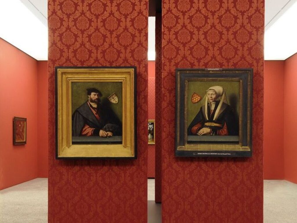 An zwei breite, direkt nebeneinander stehende, mit roter Barock-Tapete gestaltete Säulen sind das Selbstporträt des Malers Ludger Tom (links) und ein Gemälde seiner Frau Anna (rechts) aus der Zeit von um 1500 angebracht. Sie hängen so nebeneinander, dass sich beide anschauen. Ausgestattet mit gehobener Kleidung, Schmuck und dem Wappen der Familie präsentiert sich das Paar stolz als selbstbewusster Teil der Gesellschaft.
