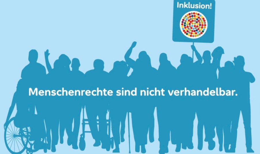 Das Banner zeigt auf hellblauem Hintergrund die etwas dunkler eingefärbte Silhouette einer Gruppe unterschiedlicher Menschen, die teilweise im Rollstuhl sitzen, einen Rollator nutzen und die Arme erhoben haben. Über ihnen ist das Motto „Menschenrechte sind nicht verhandelbar“ und eine Person reckt ein Plakat mit der Aufschrift „Inklusion“ und der Darstellung eines Kreises mit vielen bunten Kugeln in die Höhe.