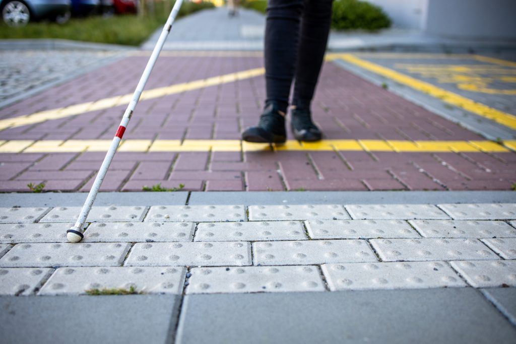 Detailansicht eines Blindenstocks der Markierungen auf einem Gehweg abfährt.