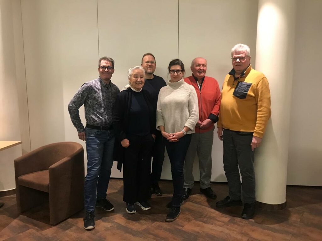 Die Vorstandsmitglieder haben sich vor einer hellen Wand nebeneinander zum Gruppenfoto aufgestellt und lächeln in die Kamera.