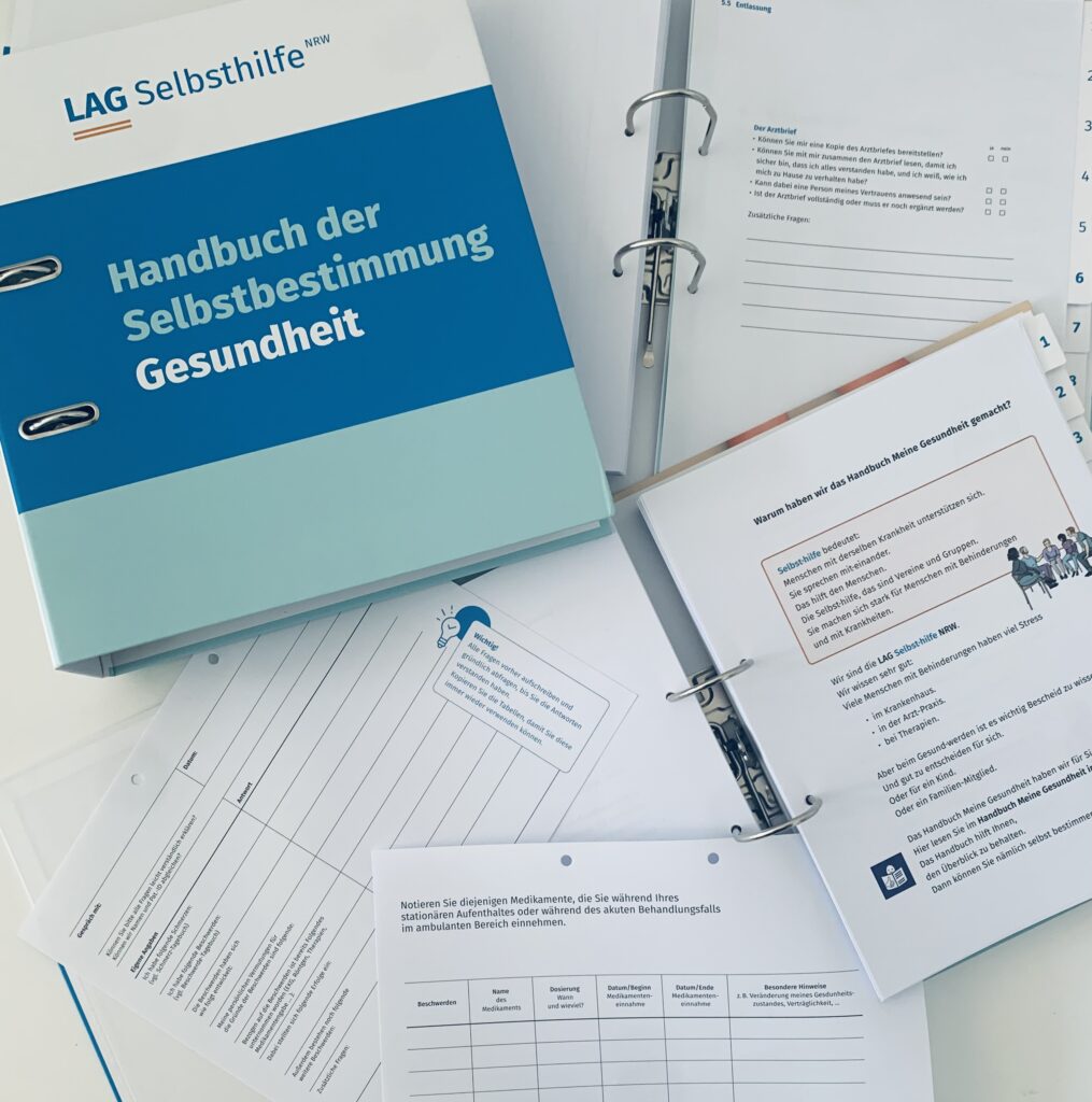 Neben dem Ringordner mit dem weiß-blau-mint gestreiften Cover des „Handbuch der Selbstbestimmung – Gesundheit“ der LAG Selbsthilfe NRW liegen zwei weitere aufgeschlagene Exemplare sowie zwei lose, ausgeheftete Blätter. Diese zeigen beispielsweise Checklisten für das Aufnahmegespräch, über eingenommene Medikamente während der Behandlung und Fragen zur Entlassung sowie eine Erklärung in Leichter Sprache, warum die Inhalte für Patient*innen wichtig sind.