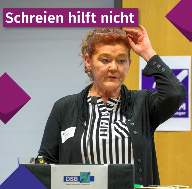 Unter der lila hinterlegten Überschrift „Schreien hilft nicht“ ist eine ältere Frau an einem Rednerpult mit DSB-Logo zu sehen. Sie trägt eine schwarz-weiße Bluse unter einer leichten anthrazitfarbenen Strickjacke und schiebt ihre hellbraune Hornbrille beim Sprechen mit der rechten Hand über den Kopf auf ihre rötlich gefärbten, lockig nach hinten gebundenen Haare.