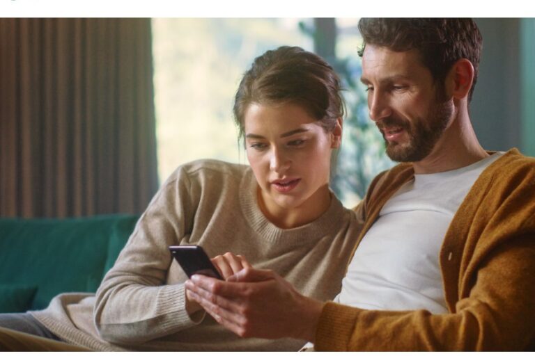 Das Poster für die Plattform zeigt ein ca. 30-jähriges Paar zu Hause auf dem Sofa. Der Mann hat dunkle Haare, einen Bart, trägt eine offene ockerfarbene Strickjacke über einem weißen T-Shirt und hält ein Handy in der linken Hand. Die Frau mit langen, zu einem Zopf gebundenen Haaren und einem beigen Pullover beugt sich zu ihm rüber, um den Bildschirm zu berühren, auf den beide schauen. Darunter steht auf weißem Hintergrund der Titel „Sie suchen Unterstützung bei Long COVID?“ und oben sind die blau gestalteten Logos der BAG SELBSTHILFE sowie der Long COVID VERNETZUNGSSTELLE abgebildet.
